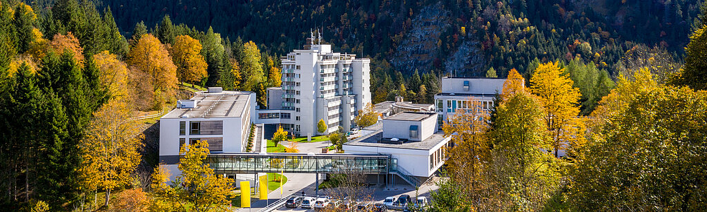 Klinik Oberammergau (Außenaufnahme) mitten im Herbstwald, im Hintergrund ist der Berg Laber zu sehen