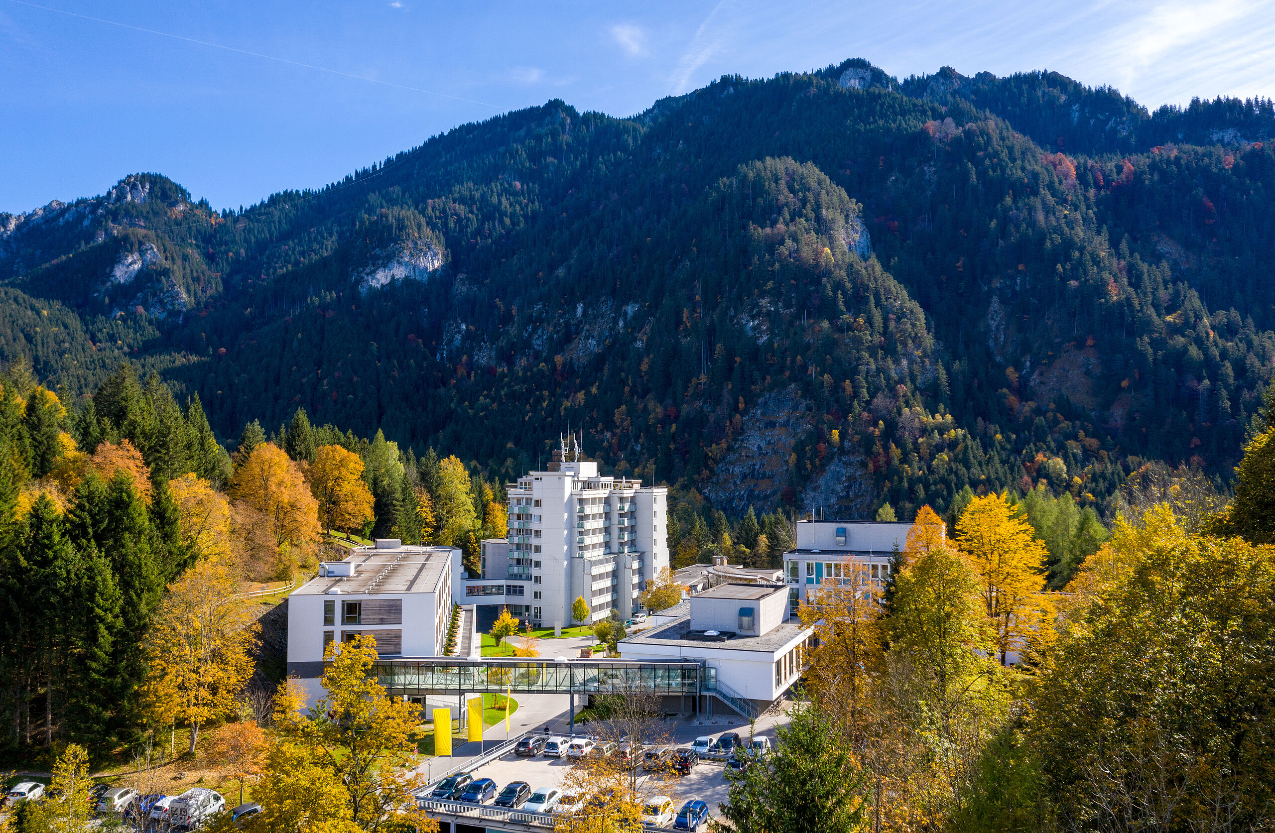 Klinik Oberammergau (Außenaufnahme) mitten im Herbstwald, im Hintergrund ist der Berg Laber zu sehen
